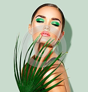 Beauty woman with natural green palm leaf. Portrait of model girl with perfect makeup, green eyeshadows