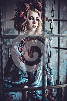 Beauty woman in the palace. Luxurious fashion stylish girl in cage. Flower dress and a wreath of flowers.