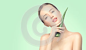 Beauty woman with perfect skin holding fresh leaf of Aloe Vera. Portrait of beautiful brunette spa girl. Skincare