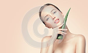 Beauty woman with perfect skin holding fresh leaf of Aloe Vera. Portrait of beautiful brunette spa girl. Skincare