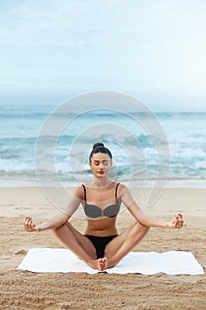 Beauty woman practices yoga and meditates in the lotus positionon the beach. Meditation.  Active Lifestyle.