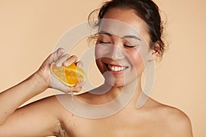 Beauty. Woman with radiant face skin squeezing orange portrait