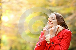 Beauty woman in red jacket grabbing scarf in a park