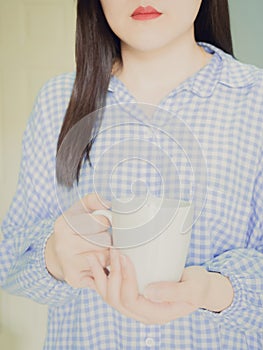 Beauty woman with red mouth in blue sleepwear hold white cup of