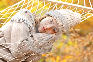 Beauty woman resting on hammock in autumn looks at you