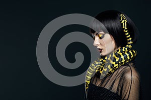 Beauty woman short haircut python yellow snake on her neck. A yellow snake on the shoulders of a girl. Beauty yellow eye shadow