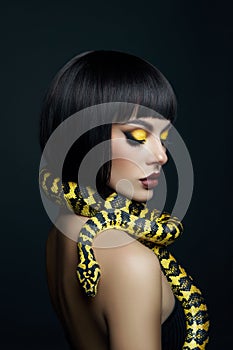 Beauty woman short haircut python yellow snake on her neck. A yellow snake on the shoulders of a girl. Beauty yellow eye shadow