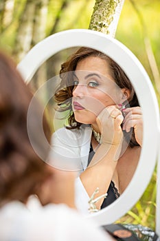 A beauty woman sitting and looking in the mirror in the forest, morning of the bride, natural beauty