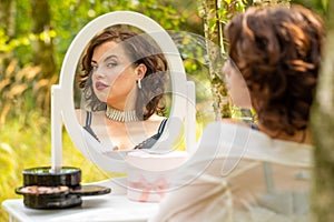 A beauty woman sitting and looking in the mirror in the forest, morning of the bride, natural beauty