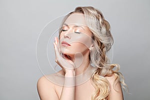 Beauty woman skin care face. Healthy blonde model with curly hair, clear skin and natural makeup on white background