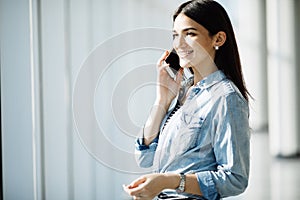 Beauty woman speak phone near panoramic windows.