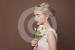 Beauty woman takes beautiful flowers in her hands on brown background