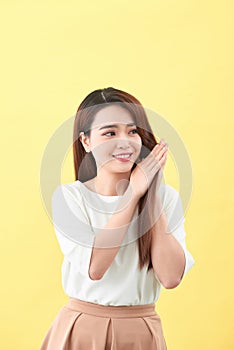 Beauty woman touch her long hair isolated on yellow background, asian beauty