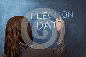 Beauty woman writing a 'ELECTION DAY' on blue chalkboard