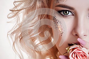 Beauty women portrait. half face of young curly blond woman with pastel manicure and perfect art make-up with glitter