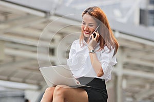 Beauty young Asian business woman using laptop and mobile smart phone for job at outside office.