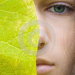 Beauty young blonde woman with green eyes without make up. Teen girl model and big green leaf