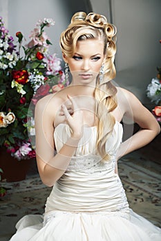 Beauty young bride alone in luxury vintage interior with a lot of flowers, makeup and creative hairstyle