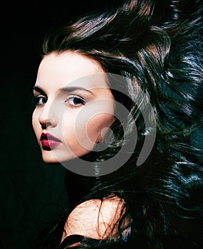 Beauty young brunette woman with curly flying hair, femme fatal