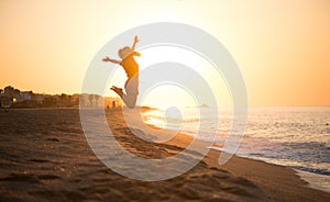 Beauty young happy woman jumping, sea side. Girl\'s silhouette on a summer beach over sunrise