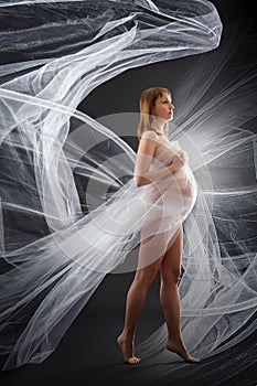 Beauty and of young pregnant woman with blowing white material