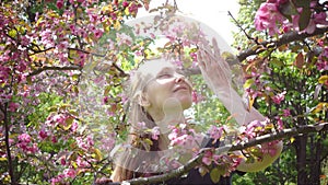 Beauty young woman enjoying nature in spring apple orchard, happy beautiful girl in garden with blooming apple trees