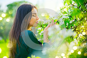 Beauty young woman enjoying nature in spring apple orchard, Happy beautiful girl in a garden with blooming fruit trees