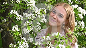 Beauty young woman enjoying nature in spring apple orchard, Happy Beautiful girl in Garden with blooming trees. Portrait of Beauti