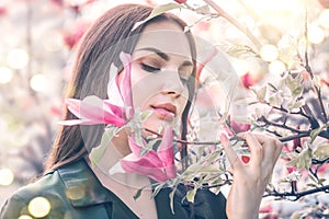 Beauty young woman enjoying nature in spring spring magnolia flowers. Beautiful brunette girl in Garden with blooming magnolias
