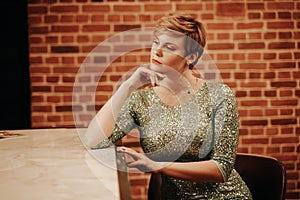 Beauty young woman portrait waiting someone at a bar. Plus size girl in a glitter party dress alone in the cafe.