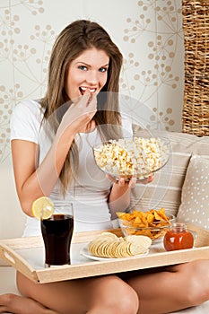 Beauty young woman sitting on sofa and having dinn