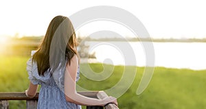 Beauty young woman standing on a wooden balcony watch the sunset or sunlight