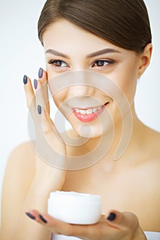 Beauty Youth Skin Care Concept - Close up Beautiful Caucasian Woman Face Portrait applying some cream to her face for skin care.