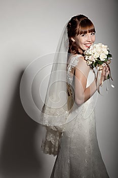 A beautyful bride holding her bouquet from roses and smiling