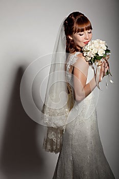 A beautyful bride looks down at her bouquet from roses.