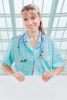 Beautyful toothy smiling female doctor with white placard