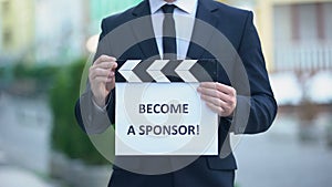 Become a sponsor phrase on clapperboard in hands of producer, independent movie