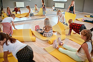 Becoming flexible. Group of children preparing for yoga class in the dance studio