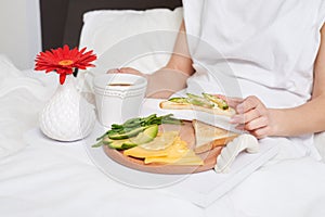 Bed breakfast with tea, avocado, cheese on tray decorated with r