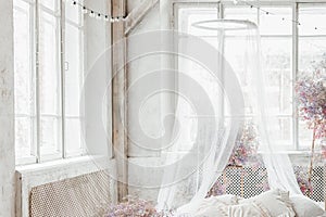 A bed in a bright bedroom in pastel colors in boho style, the trending color of 2023. The room is decorated with lilac and pink