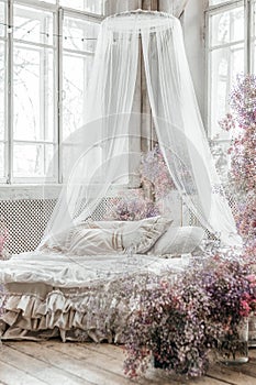 A bed in a bright bedroom in pastel colors in boho style, the trending color of 2023. The room is decorated with lilac and pink