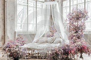 A bed in a bright bedroom in pastel colors in boho style, the trending color of 2023. The room is decorated with lilac and pink