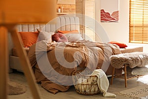 Bed with brown linens in cozy bedroom. Interior design