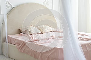 The bed is covered with a pink blanket and stands in a room flooded with white light