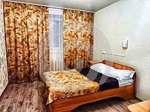 Bed in a Cozy Hotel Room. Background with room of Small, poor hotel or in house
