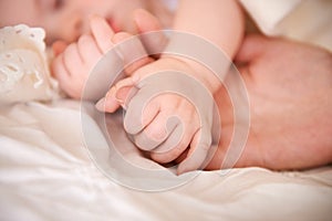 Bed, holding hands and parent with infant, care and support with maternity, health and wellness at home. Fingers, family