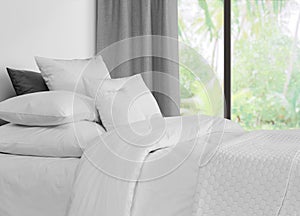 Bed with linen against a window with grey curtains