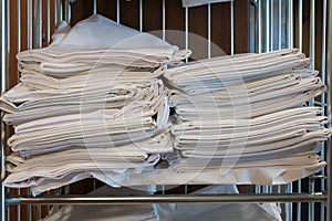 Bed linen, clean, ironed and stacked, on a shelf in a metal rack.