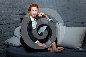 On the bed a man with freckles and red hair.