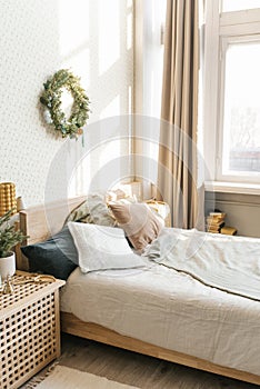 A bed with pillows and Christmas decorations in the bedroom in a Scandinavian style. Interior of the house